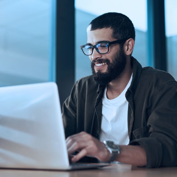Smiling man sitting at a desk working on a laptop