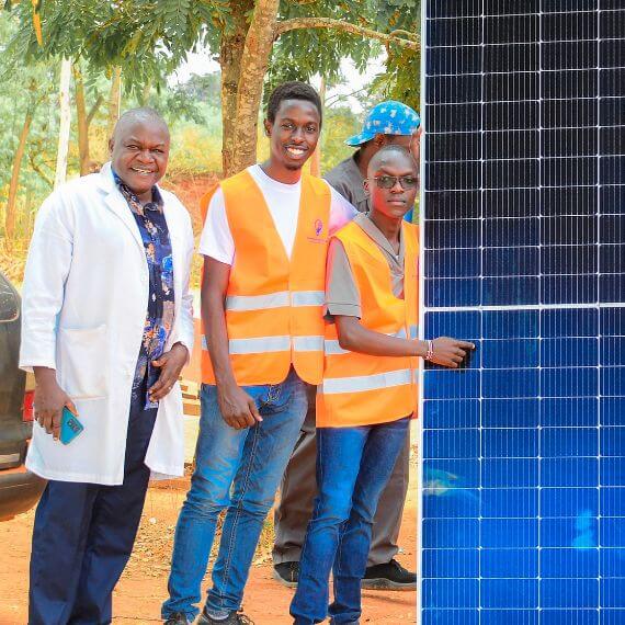 Volunteers posing with a large solar panel