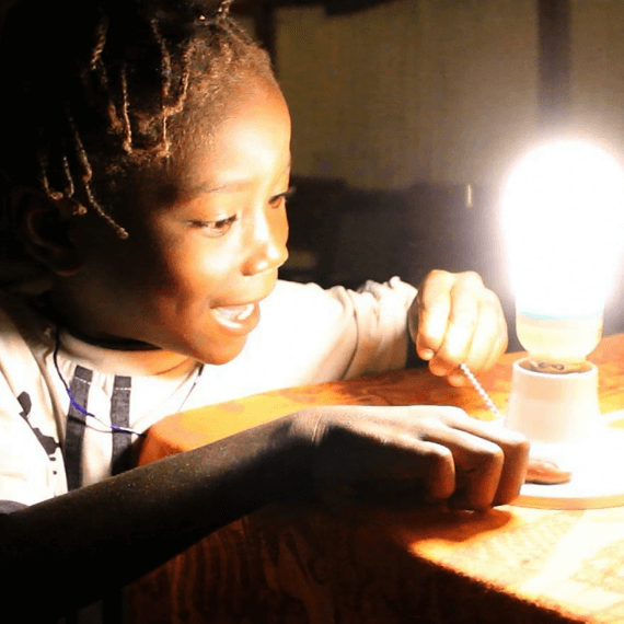 Young black girl smiling as she turns on a lightbulb in the dark